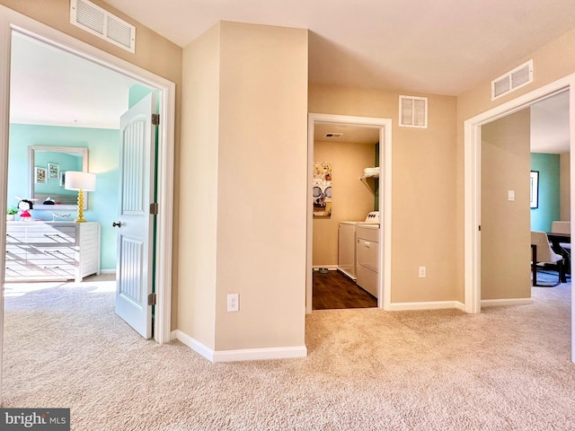 hallway featuring washer and dryer, visible vents, and carpet floors