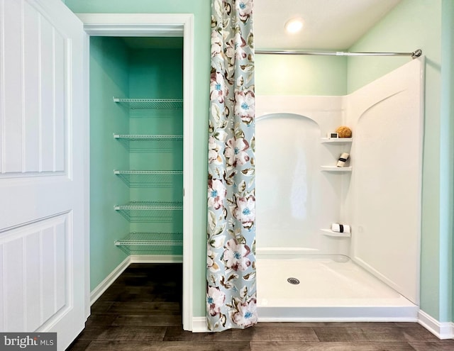 bathroom featuring curtained shower, baseboards, and wood finished floors