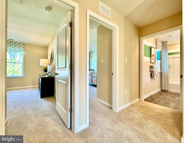 hall with visible vents, baseboards, and carpet floors