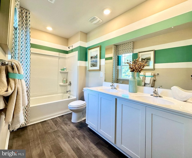 bathroom with double vanity, toilet, wood finished floors, and a sink