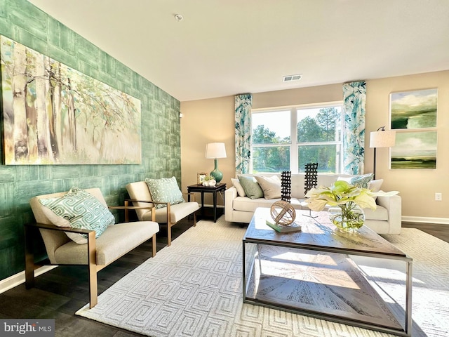 living area featuring wood finished floors, baseboards, visible vents, an accent wall, and tile walls