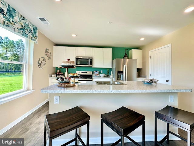 kitchen with visible vents, light wood-style flooring, appliances with stainless steel finishes, white cabinets, and a sink