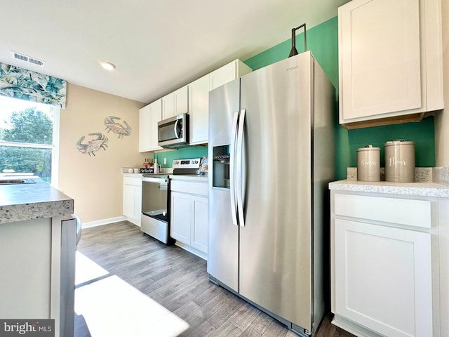 kitchen featuring visible vents, light wood finished floors, white cabinetry, appliances with stainless steel finishes, and light countertops