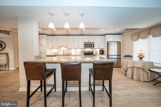 kitchen featuring a kitchen bar, white cabinets, visible vents, and appliances with stainless steel finishes