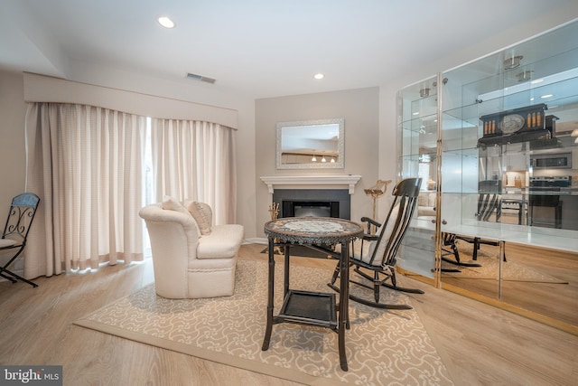 sitting room with recessed lighting, visible vents, wood finished floors, and a fireplace