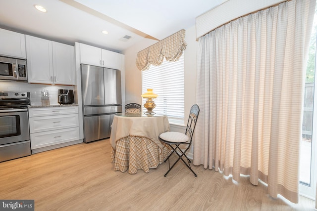 kitchen with light wood finished floors, decorative backsplash, recessed lighting, white cabinets, and stainless steel appliances