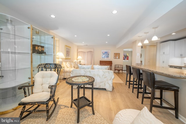 living area with recessed lighting, baseboards, and light wood-style flooring