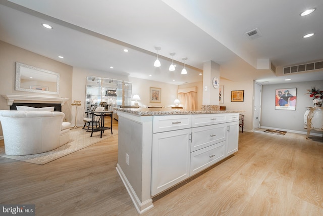 kitchen featuring light wood-type flooring, visible vents, open floor plan, and white cabinetry