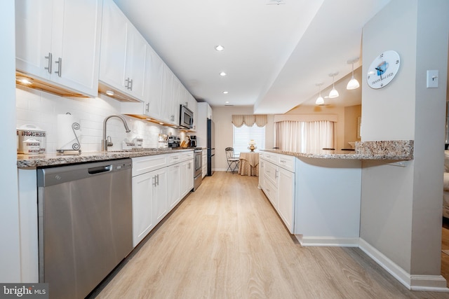 kitchen featuring light wood-type flooring, a sink, white cabinets, appliances with stainless steel finishes, and tasteful backsplash