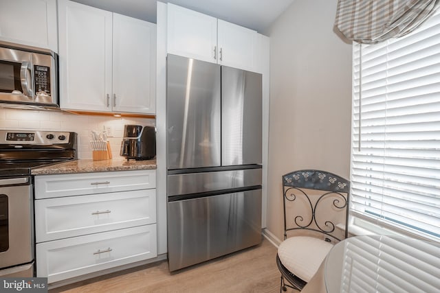 kitchen with white cabinets, light stone counters, tasteful backsplash, and appliances with stainless steel finishes