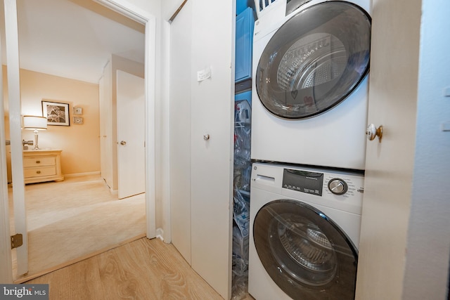 clothes washing area featuring laundry area, wood finished floors, and stacked washer / drying machine