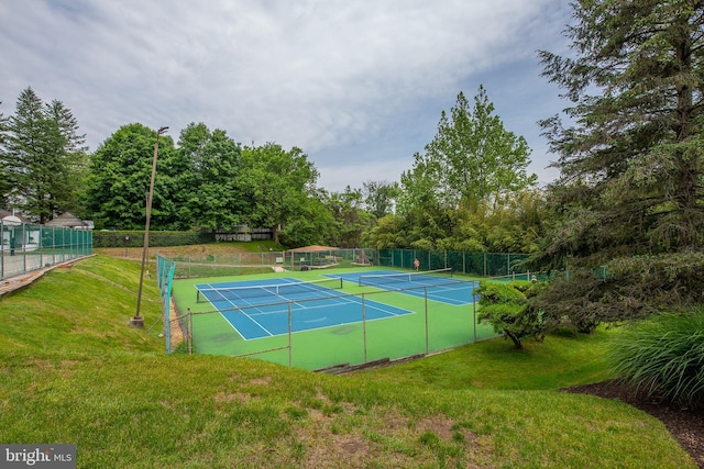 view of sport court with fence and a lawn