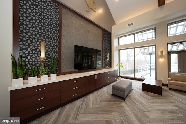 living area with a healthy amount of sunlight, visible vents, and high vaulted ceiling