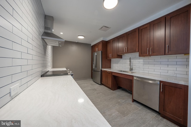 kitchen with visible vents, a sink, wall chimney range hood, stainless steel appliances, and light countertops