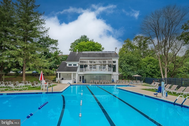 community pool with a patio area and fence