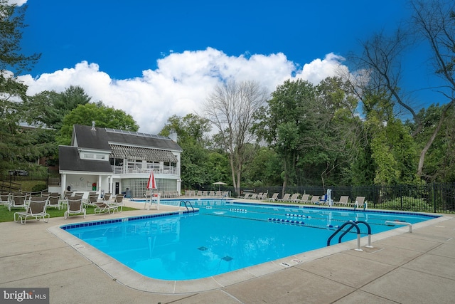 community pool with a patio and fence