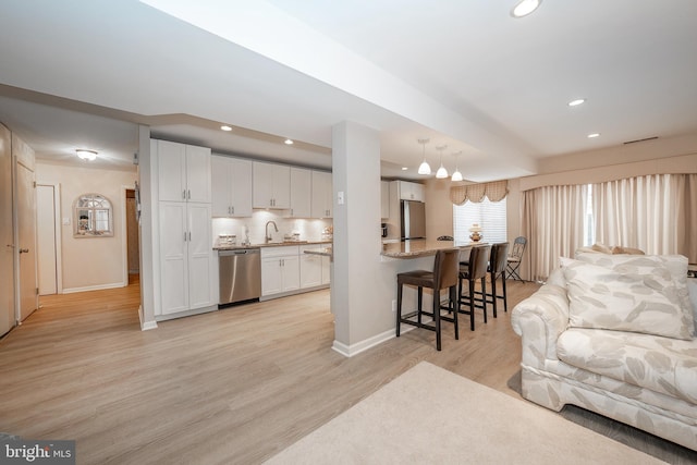 living area with recessed lighting, light wood-style floors, and baseboards