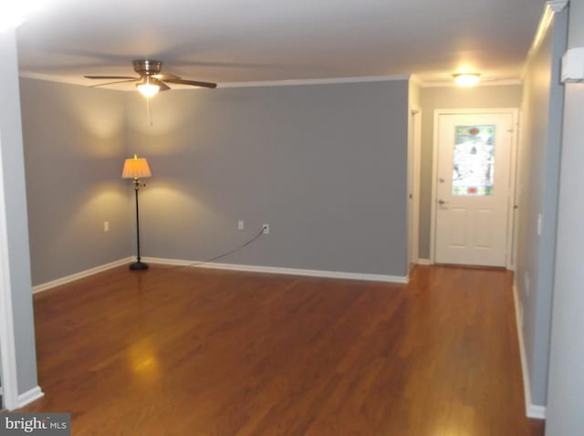 empty room featuring crown molding, wood finished floors, baseboards, and ceiling fan