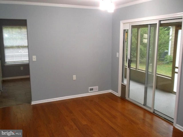 unfurnished room with plenty of natural light, wood finished floors, visible vents, and ornamental molding