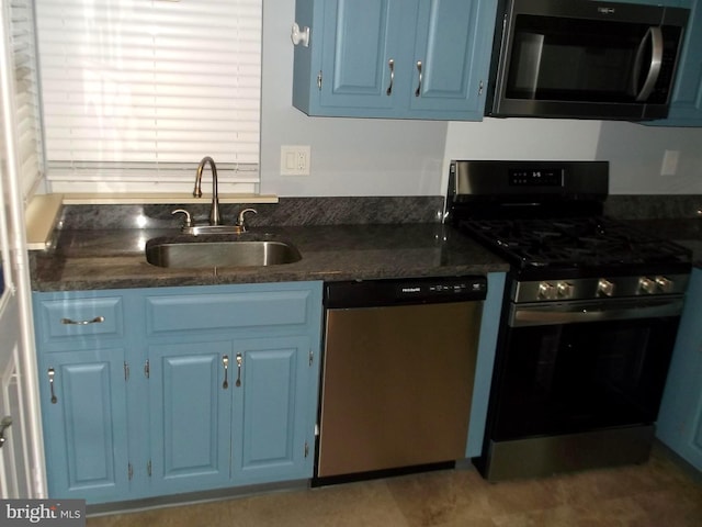 kitchen with dark countertops, blue cabinetry, stainless steel appliances, and a sink