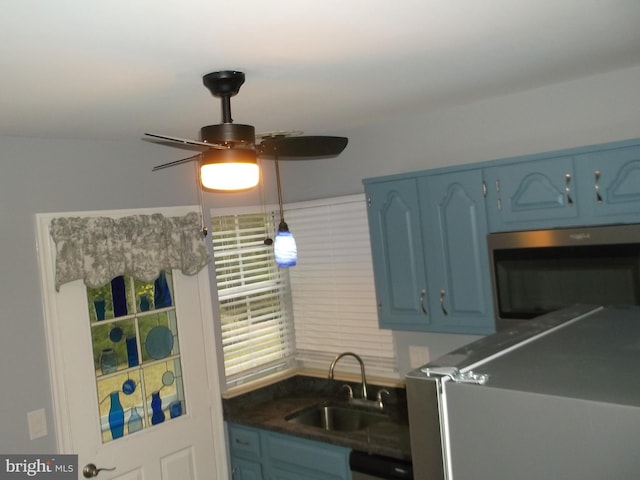 kitchen featuring stainless steel microwave, blue cabinetry, a ceiling fan, and a sink