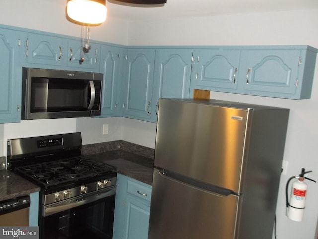 kitchen with dark countertops, blue cabinetry, and appliances with stainless steel finishes