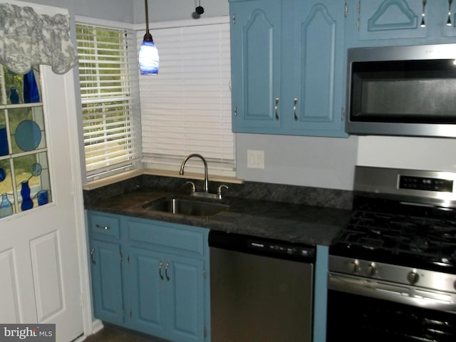 kitchen with a sink, dark countertops, blue cabinets, and stainless steel appliances