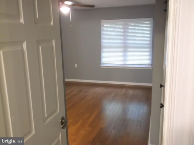 unfurnished room with baseboards, wood finished floors, and a ceiling fan