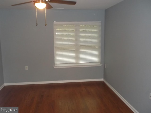 spare room with wood finished floors, a ceiling fan, and baseboards