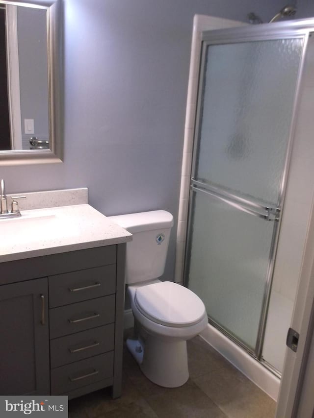 full bath with tile patterned floors, toilet, a stall shower, and vanity