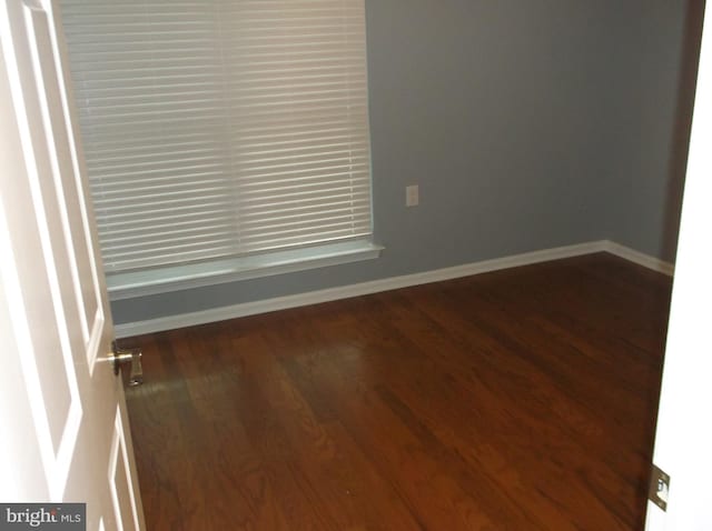 spare room featuring baseboards and wood finished floors