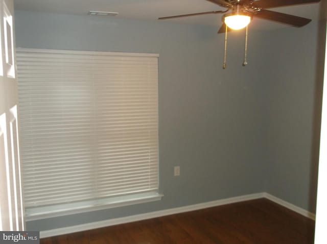 unfurnished room featuring dark wood-style floors, baseboards, visible vents, and ceiling fan