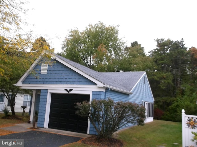 view of front of home featuring aphalt driveway, a garage, and roof with shingles