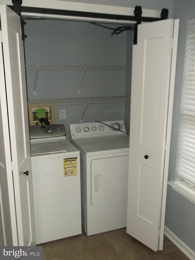 clothes washing area featuring washing machine and clothes dryer, laundry area, and a barn door