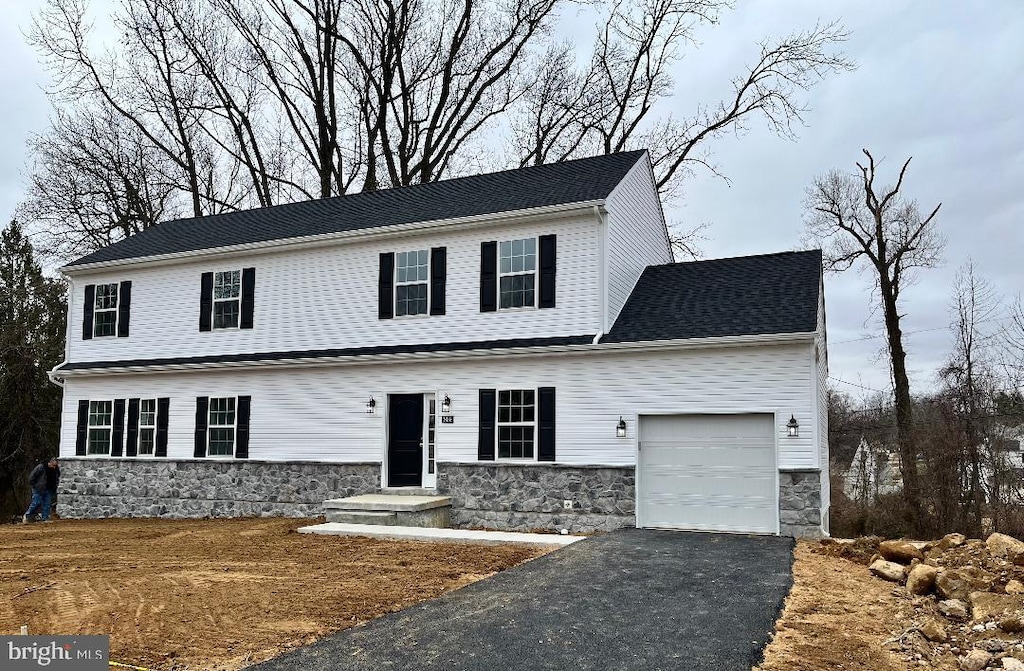 view of front facade featuring aphalt driveway, stone siding, and an attached garage