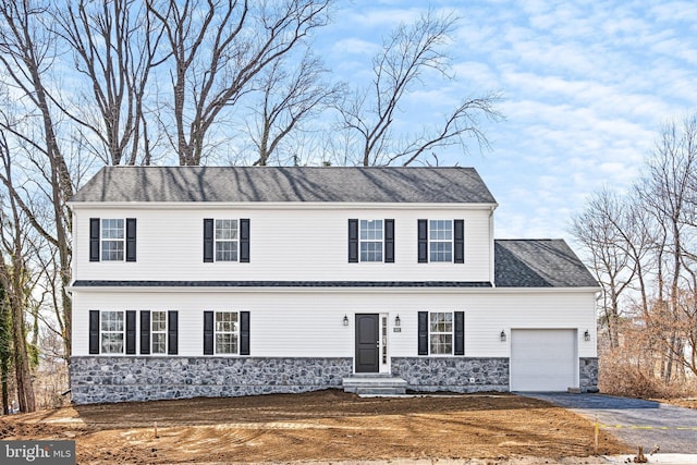 view of front of property featuring a garage, stone siding, and aphalt driveway