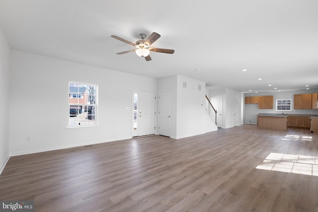 unfurnished living room featuring stairway, baseboards, light wood finished floors, recessed lighting, and ceiling fan