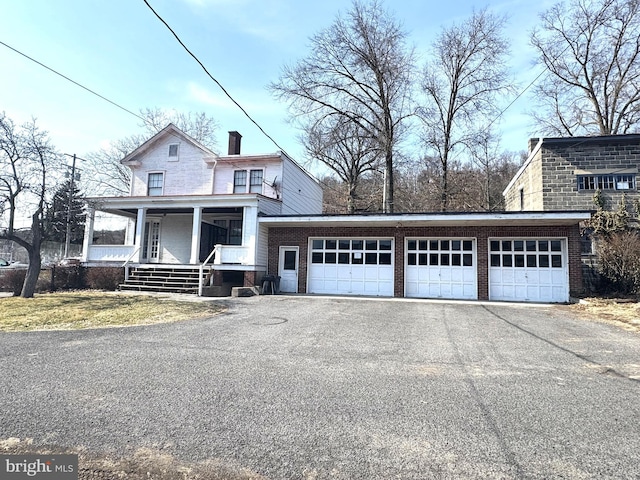 view of front of home with brick siding, a porch, and a chimney