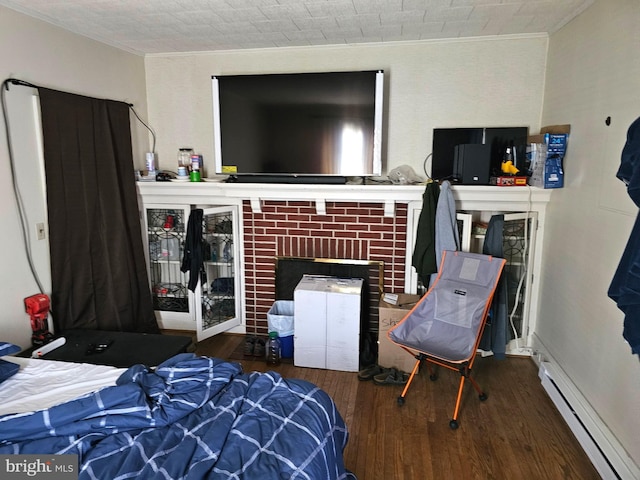 bedroom with crown molding, a brick fireplace, wood finished floors, and a baseboard radiator