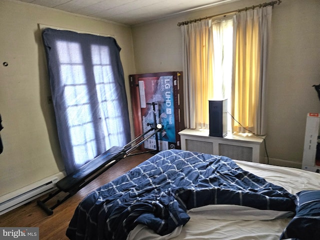 bedroom featuring a baseboard heating unit and wood finished floors