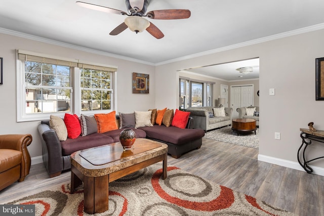 living room with a wealth of natural light, crown molding, baseboards, and wood finished floors