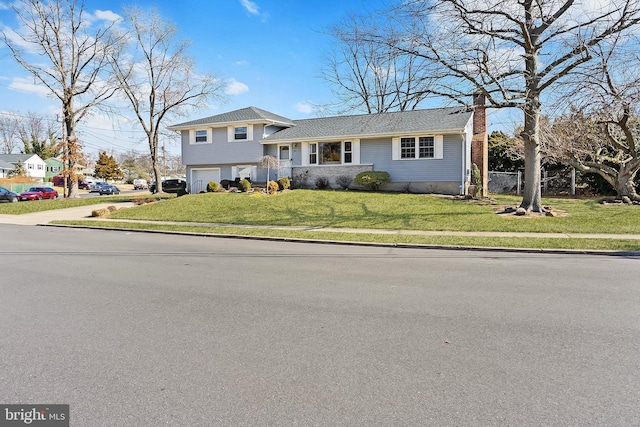 tri-level home featuring a front yard, a garage, and a chimney