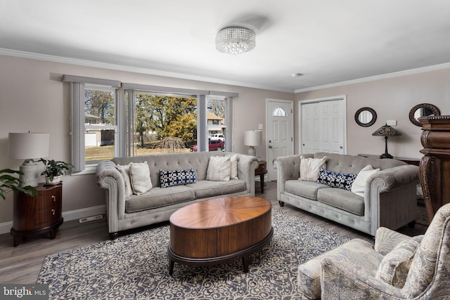 living area with visible vents, wood finished floors, baseboards, and ornamental molding