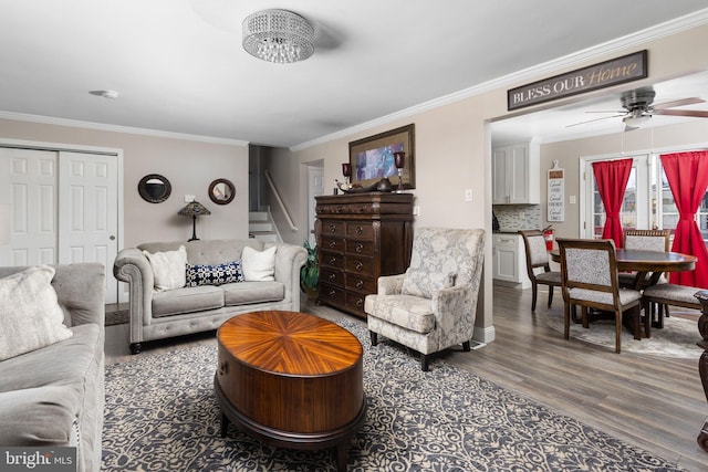 living area featuring stairs, crown molding, ceiling fan, and wood finished floors