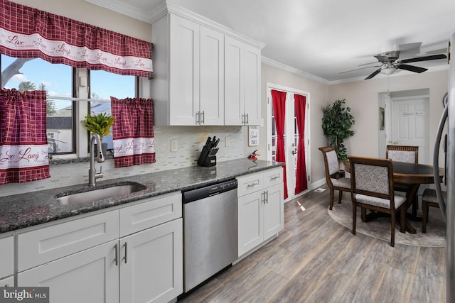 kitchen with ornamental molding, light wood-style flooring, a sink, stainless steel dishwasher, and decorative backsplash