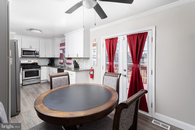 dining area with wood finished floors, baseboards, visible vents, ornamental molding, and ceiling fan