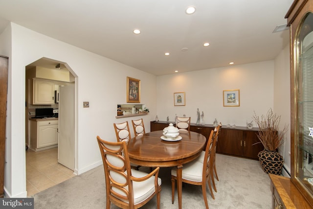 dining room with baseboards, recessed lighting, arched walkways, and light carpet