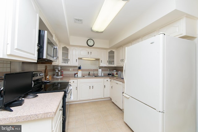 kitchen featuring white appliances, a sink, decorative backsplash, light countertops, and glass insert cabinets