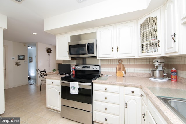 kitchen with decorative backsplash, light countertops, white cabinets, and stainless steel appliances