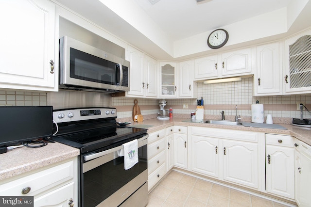 kitchen featuring decorative backsplash, white cabinets, appliances with stainless steel finishes, and a sink